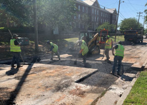 Workers use shovels to spread and place hot asphalt in a road section in North Carolina.