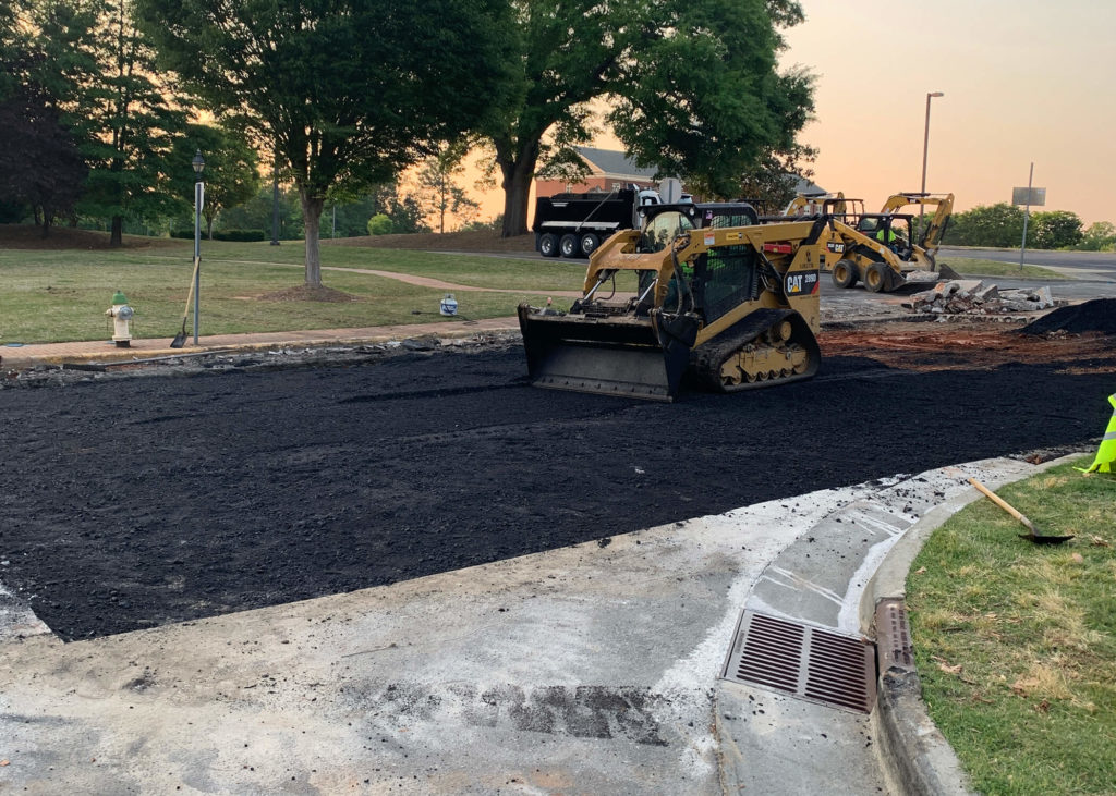 A skidloader smoothes freshly placed asphalt pavement during a street repair in eastern North Carolina.