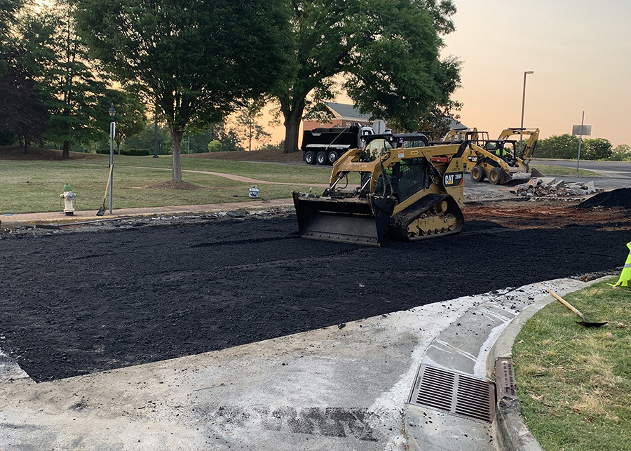 A skidsteer smooths a fresh asphalt patch during a road repair in North Carolina.