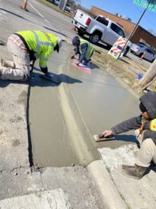 Workers finish a new concrete curb, gutter, and sidewalk patch by hand in Wilson County, NC.