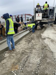 Workers hand finish a newly placed concrete curb at the Kinston, NC, airport.