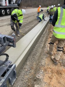 Workers observe a newly placed concrete curb near Wendell, NC.