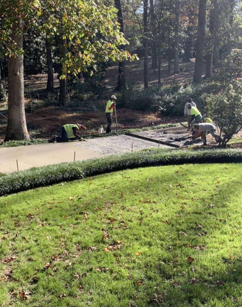 Concrete finishers use hand tools to float placed concrete inside wooden forms for a residential driveway.