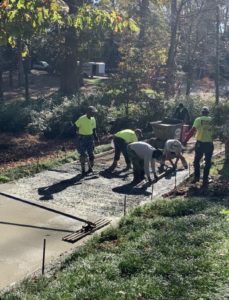 A concrete crew uses tools to place concrete inside wooden forms for a residential driveway in Wilson, NC.
